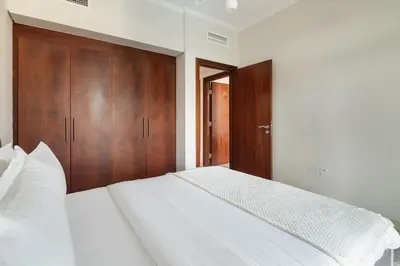 a bedroom with a white bed and wooden cabinets at Pool View 2BR with Big Balcony in Dubai