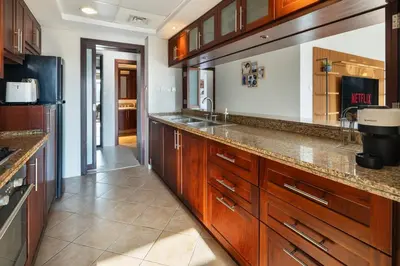 a large kitchen with wooden cabinets and a sink at Pool View 2BR with Big Balcony in Dubai