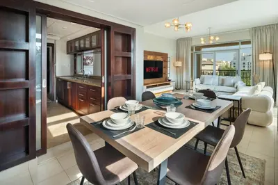 a living room with a wooden table and chairs at Pool View 2BR with Big Balcony in Dubai