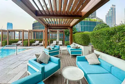 a patio with blue couches and a pool at Vogue Downtown Address Residence near Burj Khalifa and Dubai Mall, Two Bedroom Apartment with Balcony and Burj Khalifa view, Access to all Amenities in Dubai