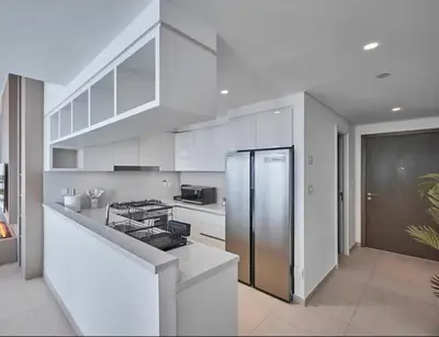 a white kitchen with a stainless steel refrigerator at Premium Burj Vista Downtown Apartments with Burj Khalifa View in Dubai