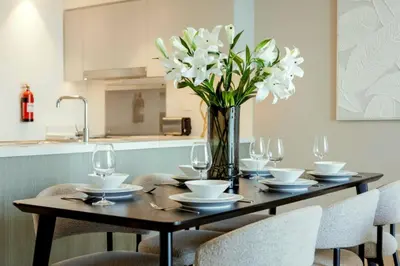 a dining room table with chairs and a vase with white flowers at Spacious Luxury Apartments at Burj Vista with Direct Burj Khalifa Views in Dubai
