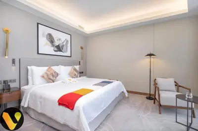 a bedroom with a large white bed and a chair at Vogue Downtown Address Residence near Burj Khalifa and Dubai Mall, Two Bedroom Apartment with Balcony and City Skyline view, Access to all Amenities in Dubai