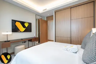 a bedroom with a white bed and a tv on the wall at Vogue Downtown Address Residence near Burj Khalifa and Dubai Mall, Two Bedroom Apartment with Balcony and City Skyline view, Access to all Amenities in Dubai