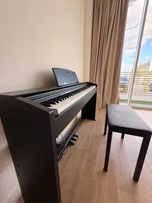 a piano in a room with a chair and a laptop at Quiet Villa 3 Br in Dubai