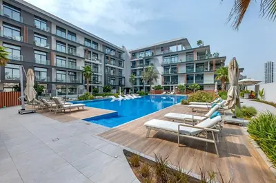 a hotel with a swimming pool with lounge chairs and a building at Waves - Boho Style Chic Studio With Balcony in JVC in Dubai