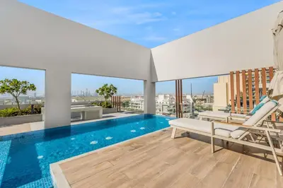 a living room with a swimming pool and a chair at Waves - Boho Style Chic Studio With Balcony in JVC in Dubai