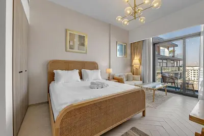 a bedroom with a large bed and a living room at Waves - Boho Style Chic Studio With Balcony in JVC in Dubai