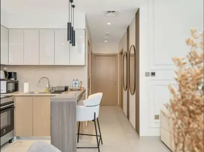 a kitchen with white cabinets and a counter with chairs at Grand Burj Vista Downtown Apartment with Burj Khalifa View in Dubai