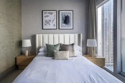 a bedroom with a large white bed with two lamps at Grand Burj Vista Downtown Apartment with Burj Khalifa View in Dubai