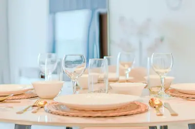 a table with plates and wine glasses on it at TRPS - The Grand, Dubai Creek Harbour - Luxury High-Floor 1BR, Creek & Skyline View in Dubai