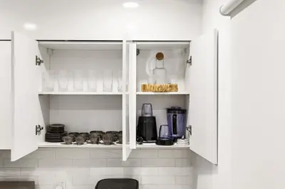 a white kitchen with white cabinets and appliances at Elegant 1BR with Pool Gym & Burj Khalifa Views in Dubai