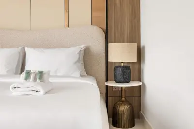 a bedroom with a white bed with a lamp and a side table at Elegant 1BR with Pool Gym & Burj Khalifa Views in Dubai