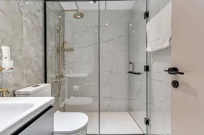 a bathroom with a shower with a toilet and a sink at Skyz by Danube Chic 2BR with Balcony & Pool Access in Dubai
