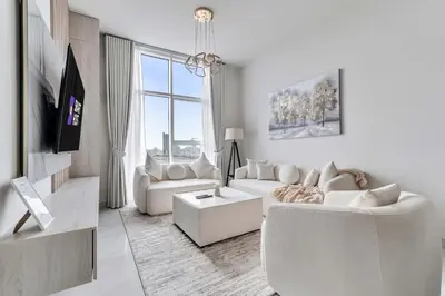 a living room with white furniture and a large window at Skyz by Danube Chic 2BR with Balcony & Pool Access in Dubai