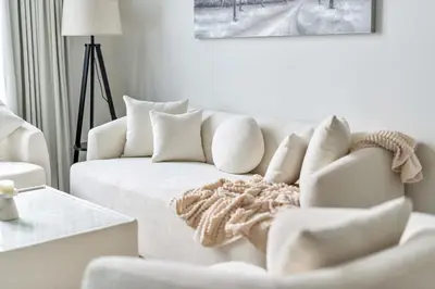 a white living room with a white couch and a table at Skyz by Danube Chic 2BR with Balcony & Pool Access in Dubai