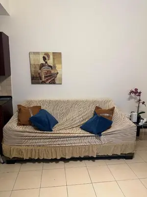 a couch in a room with blue pillows on it at Modern 1BR in JVC, 2 Baths, Pool & Gym, Fully Equipped Kitchen in Dubai