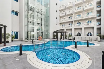 a swimming pool in front of a building at Modern 1BR in JVC, 2 Baths, Pool & Gym, Fully Equipped Kitchen in Dubai