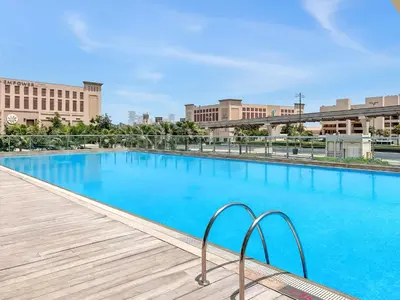 a large blue swimming pool with buildings in the background at Amazing Studio with Balcony & Marina Eye Views in Dubai