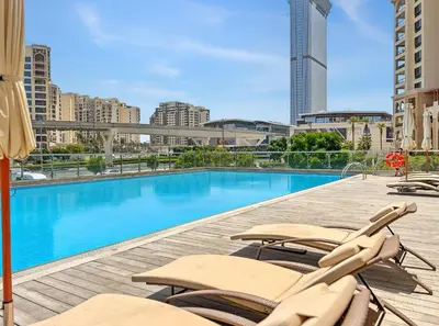 a swimming pool with chaise lounge chairs on a building at Amazing Studio with Balcony & Marina Eye Views in Dubai