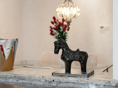 a black horse statue on a table with a vase of flowers at Skyline Select 1 Bedroom Apartment I Burj Khalifa View I Souk Al Bahar Downtown I Parking, Gym, Wi-Fi & Pool in Dubai