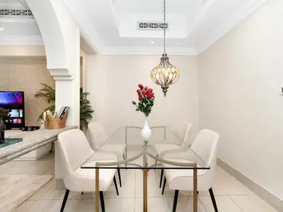 a dining room with a glass table and white chairs at Skyline Select 1 Bedroom Apartment I Burj Khalifa View I Souk Al Bahar Downtown I Parking, Gym, Wi-Fi & Pool in Dubai