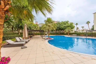 a swimming pool with chairs and umbrellas in a resort at StayShort - Chic Discovery Gardens 1Bed that Sleeps 2 in Dubai