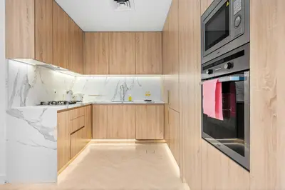 a kitchen with wooden cabinets and a sink and a microwave at StayShort - Chic Discovery Gardens 1Bed that Sleeps 2 in Dubai