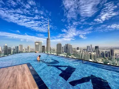 a man in a infinity pool on the top of a skyscraper at RH - Luxury 2BR at Paramount Midtown, Burj Khalifa View in Dubai