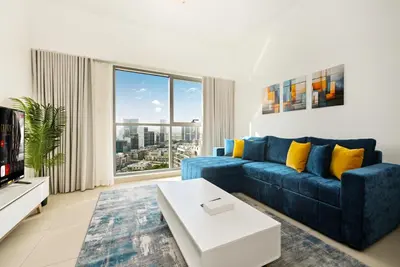 a living room with a blue couch and a large window at Modern 1BDR Apt With Balcony Pool Access And JVC in Dubai