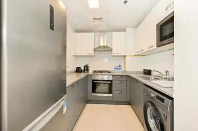 a kitchen with white cabinets and a dishwasher at Modern 1BDR Apt With Balcony Pool Access And JVC in Dubai