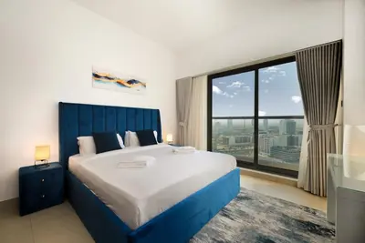 a bedroom with a large bed and a large window at Modern 1BDR Apt With Balcony Pool Access And JVC in Dubai