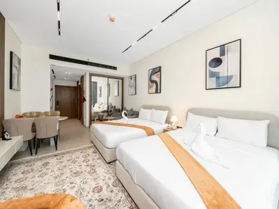 a bedroom with two beds and a living room at Luxury Studio with Private Jacuzzi & Balcony Trillionaire Residences 4 Guests in Dubai