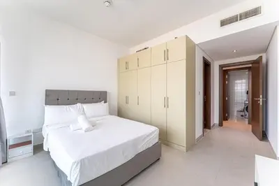 a white bedroom with a large white bed and cabinets at HAVN - 2 bed in Hilliana Tower, Jumeirah Burj View in Dubai