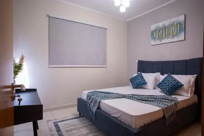 a bedroom with a bed with blue and white pillows at Luxury 2BR Haven with Panoramic Scenery - The Greens in Dubai