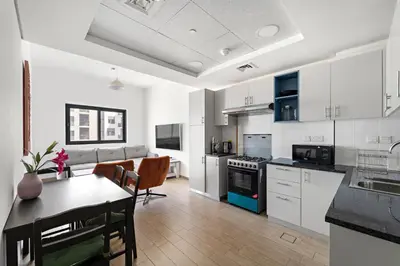 a kitchen with white cabinets and a table in a room at Modern & Cozy 2BR Apartment at The Nook 1 Near Metro in Dubai