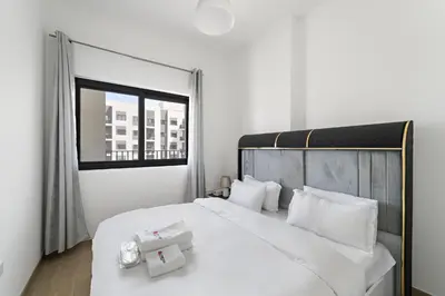 a bedroom with a large white bed with a window at Modern & Cozy 2BR Apartment at The Nook 1 Near Metro in Dubai