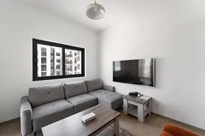 a living room with a couch and a tv at Modern & Cozy 2BR Apartment at The Nook 1 Near Metro in Dubai