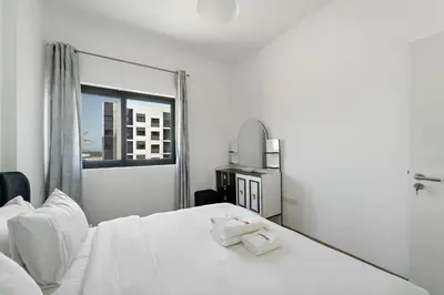 a bedroom with a white bed and a window at Modern & Cozy 2BR Apartment at The Nook 1 Near Metro in Dubai