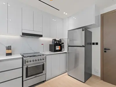 a white kitchen with a stainless steel refrigerator at Charming 2BDR Stay in Binghatti Corner- JVC in Dubai