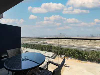 a table and chairs on a balcony with a view of a highway at Charming 2BDR Stay in Binghatti Corner- JVC in Dubai