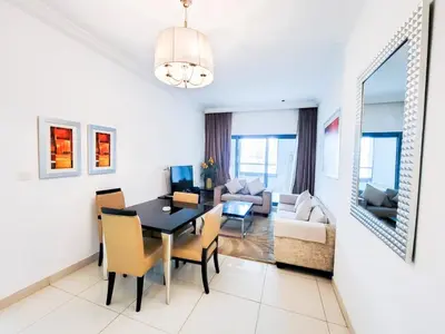 a dining room and living room with a table and chairs at DAMAC CAPITAL BAY - Blueocean Holiday Homes in Dubai