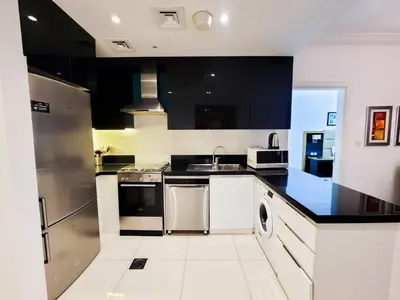 a kitchen with black and white counters and appliances at DAMAC CAPITAL BAY - Blueocean Holiday Homes in Dubai