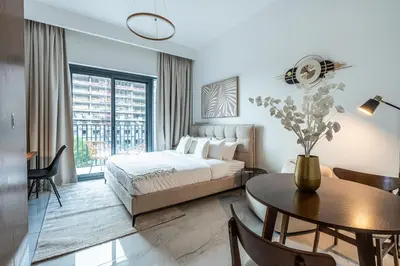 a bedroom with a bed and a table and a dining room at Exquisite studio apartment in Azizi Mirage in Dubai