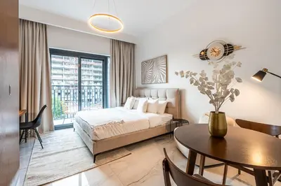 a bedroom with a bed and a table in a room at Exquisite studio apartment in Azizi Mirage in Dubai