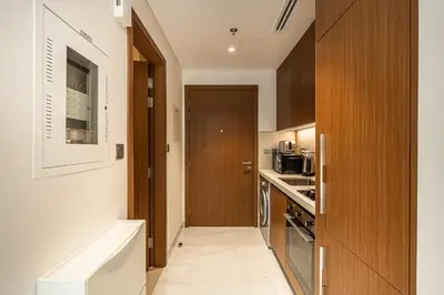 a small kitchen with wooden cabinets and a door at Exquisite studio apartment in Azizi Mirage in Dubai
