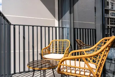 two wicker chairs and a table on a balcony at Exquisite studio apartment in Azizi Mirage in Dubai
