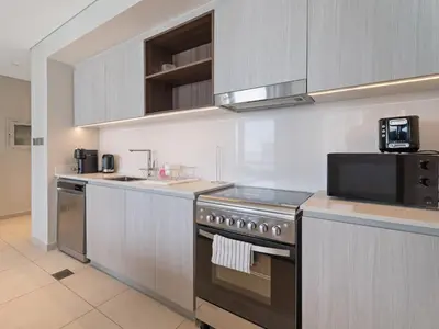 a kitchen with a stove and a microwave at Opulent Haven 2BDR w Sofa Bed Sleeps 6 In Vida-02 in Dubai