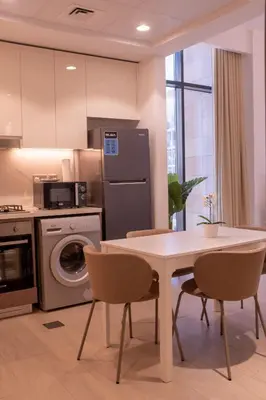 a kitchen with a table and chairs and a refrigerator at Large Beautiful One Bed Downtown Dubai in Dubai