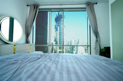 a bedroom with a large window with a view of a skyscraper at Skyline & Islands View 3BR Luxe Top Floor Noura Tower Business Bay in Dubai
